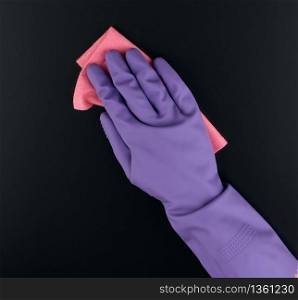 hand holds a pink rag sponge for cleaning, protective purple rubber glove is worn on the arm, close up