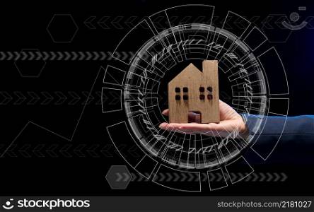 hand holds a wooden model of a house on a dark background. Real estate sale and purchase concept, rent. Insurance and mortgage