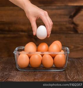 hand holds an egg against the background of packing eggs. hand holds an egg