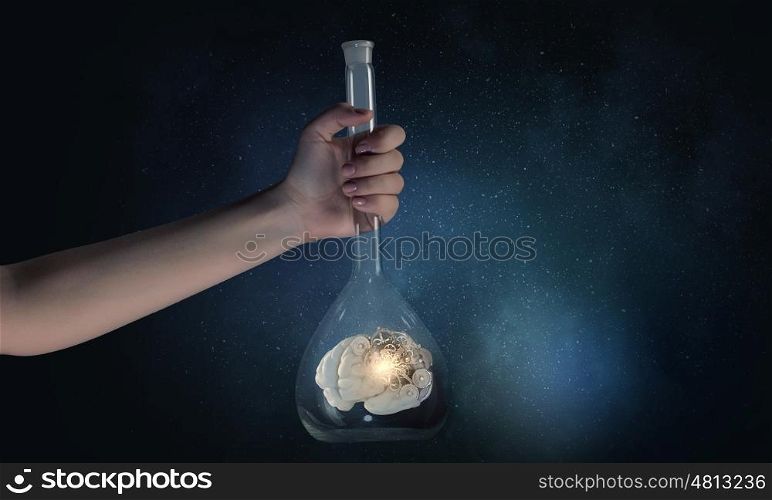 Hand holds flask with images on varied background. Flask and the objects in it