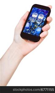 hand holds mobile phone with Christmas still life on screen isolated on white background
