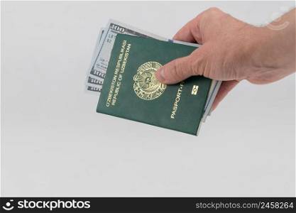 Hand holds out Uzbekistan passport with usa dollars. Concept - briber and corruption. passport of Uzbekistan, on white background