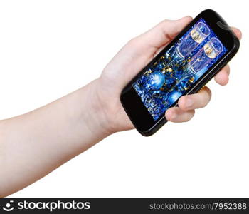 hand holds smart phone with Xmas still life on screen isolated on white background