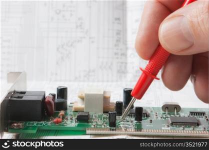 hand holds the instrument and tests electronic circuit boards