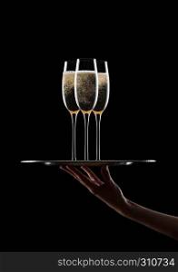 Hand holds tray with yellow champagne glasses with bubbles on black background