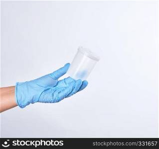 hand in a blue sterile glove holds a empty plastic container for collecting analyzes, white background