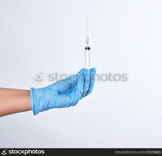 hand in a blue sterile glove holds a plastic syringe on a white background