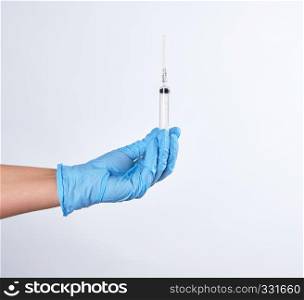 hand in a blue sterile glove holds a plastic syringe on a white background