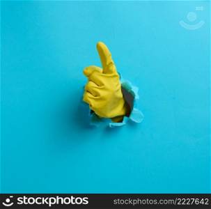 hand in a green latex glove points a finger on a blue background. Place for inscription of discounts, offer or announcement.