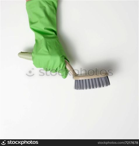 hand in a green rubber cleaning glove holds a plastic brush on a white background