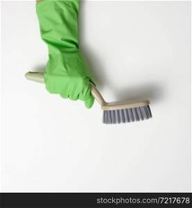 hand in a green rubber cleaning glove holds a plastic brush on a white background