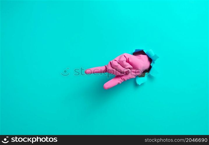 hand in a pink latex glove points a finger on a blue background. Place for inscription of discounts, offer or announcement.