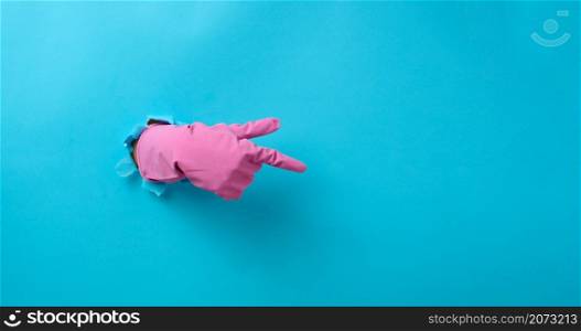 hand in a pink latex glove points a finger on a blue background. Place for inscription of discounts, offer or announcement.