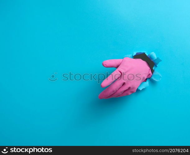 hand in a pink latex glove points a finger on a blue background. Place for inscription of discounts, offer or announcement.