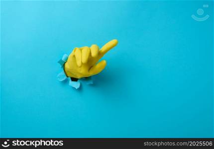 hand in a yellow latex glove points a finger on a blue background. Place for inscription of discounts, offer or announcement.