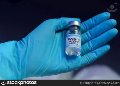 Hand in blue glove holding vaccine and syringe injection for prevention, immunization and treatment from corona virus infection.