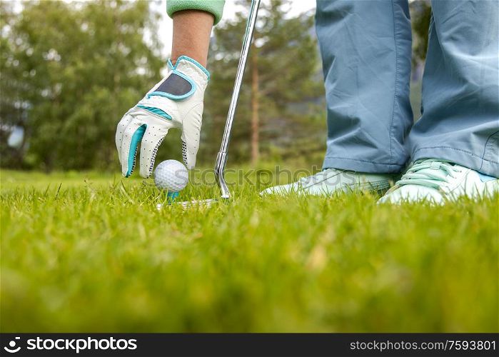 Hand in glove placing golf ball on tee