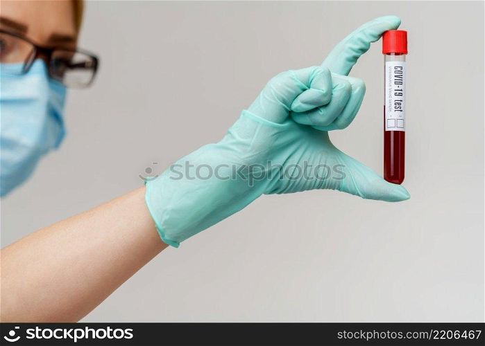 hand in latex glove holding blood in test tube close up.. hand in latex glove holding blood in test tube close up