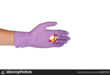 Hand in latex medical glove holding a lot of pills isolated on white. Close up. Medicine or health treatment concept.