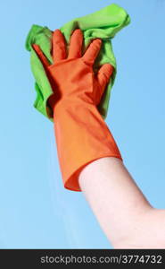 hand in orange glove cleaning window with green rag