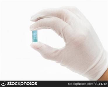 hand in white glove holds aquamarine crystal on white background