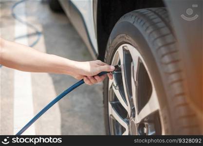 hand inflating tires of vehicle, checking air pressure and filling air on car wheel at gas station. self service, maintenance and safety transportation concept