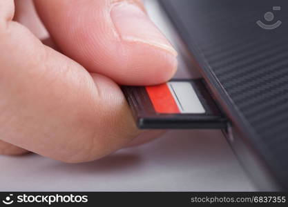 hand inserting SD card into laptop slot