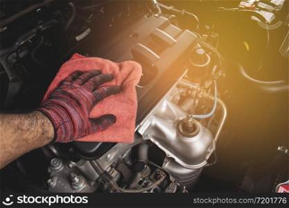 Hand is cleaning engine cover with a using red microfiber cloth,Automotive maintenance concept.
