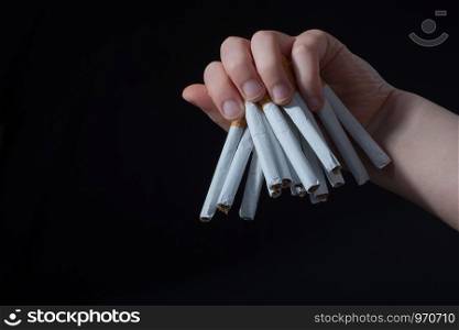 Hand is giving out bundle of cigarettes on black background