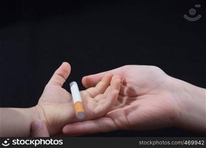Hand is giving out cigarette on a black background