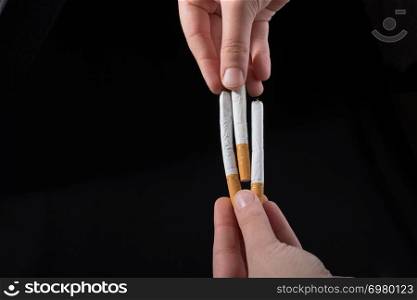 Hand is giving out cigarette on a black background