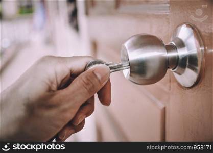 Hand is opening the door knob with the key.