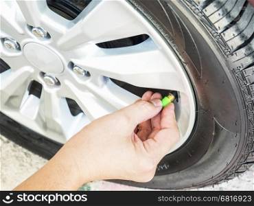 Hand is removing a green tire valve caps for nitrogen tire inflation service