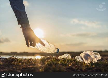 hand keeping garbage bottle for cleaning at park in morning light. eco concept