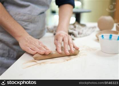 Hand-kneading technique in pottery - Woman wedging clay with hands standing behind table in studio.. Hand-kneading technique in pottery - Woman wedging clay with hands standing behind table in studio
