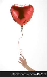 Hand Letting Go Of Heart Shaped Balloon