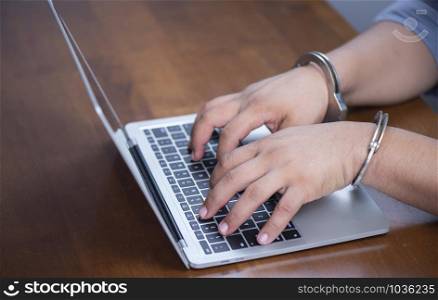 Hand lock handcuffs with laptop by on the keyboard of the notebook, electronic crime concept