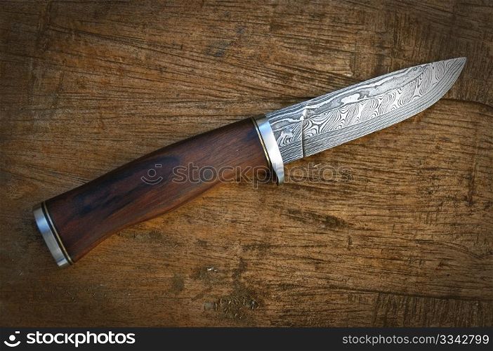 Hand made damascus knife on wooden background