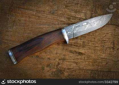 Hand made damascus knife on wooden background