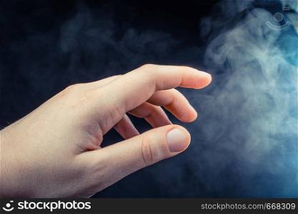 Hand making a gesture on a black smoky background