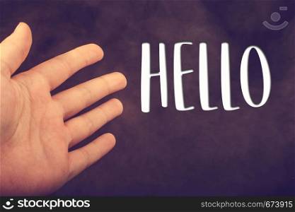 Hand making a hello welcome gesture on dark background