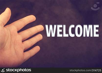 Hand making a welcome gesture on a dark background