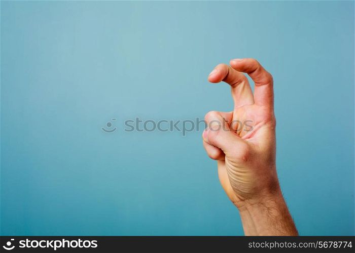 Hand making bunny ears with two fingers against blue background