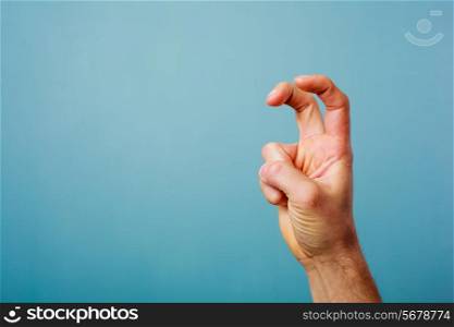 Hand making bunny ears with two fingers against blue background