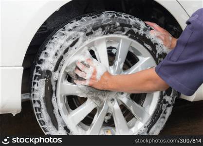 Hand man worker washing car&rsquo;s alloy wheels on a car wash