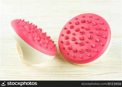 Hand massager with silicone spikes for anti-cellulite massage procedure on white wooden background. Massage brush tool for problem body zone, self-care, health care, body therapy.. Hand massager with silicone spikes for anti-cellulite massage on white wooden background.