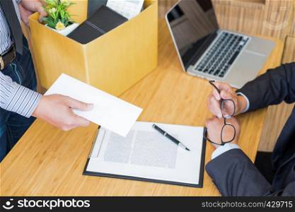 Hand of a businessman hands over a resignation letter final remuneration to executive boss on a wooden table to his boss Change of job, unemployment concept.