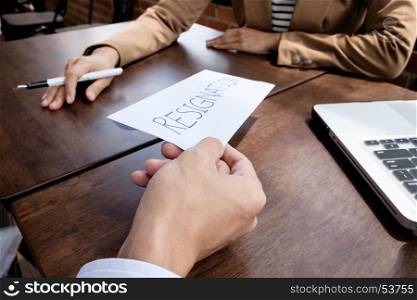 Hand of a businessman hands over a resignation letter on a wooden table to his boss.