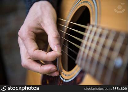 Hand of a guitar player playing acoustic guitar