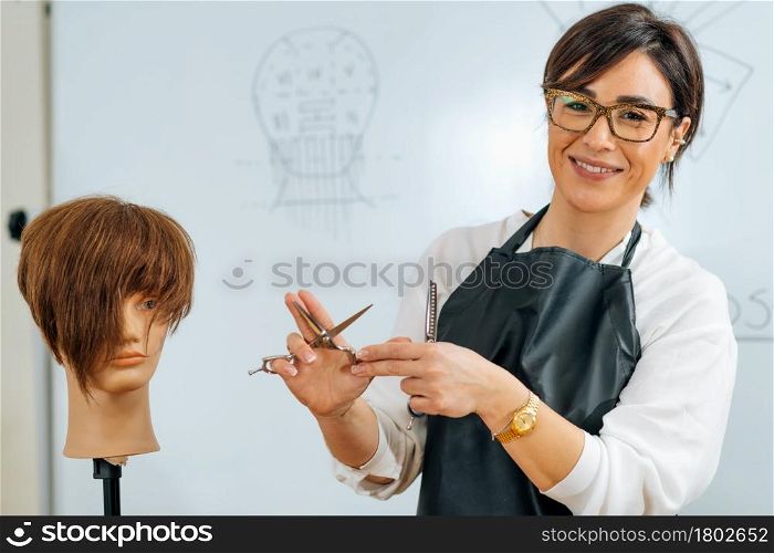 Hand of a hairdresser holding hairdressing scissors, explaining students haircutting techniques to students. Hand of a Hairdresser Holding Hairdressing Scissors, Explaining Haircutting Techniques to Students